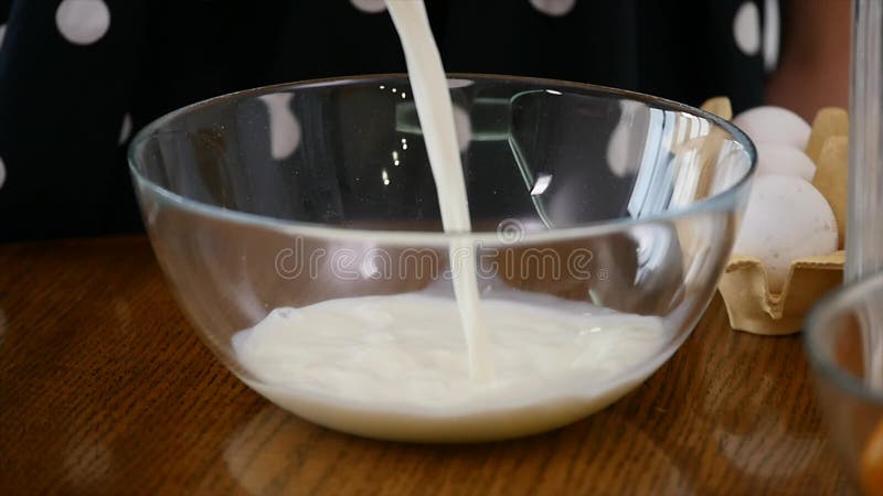 Een vrouw in de keuken aan kok Melk het gieten in kom