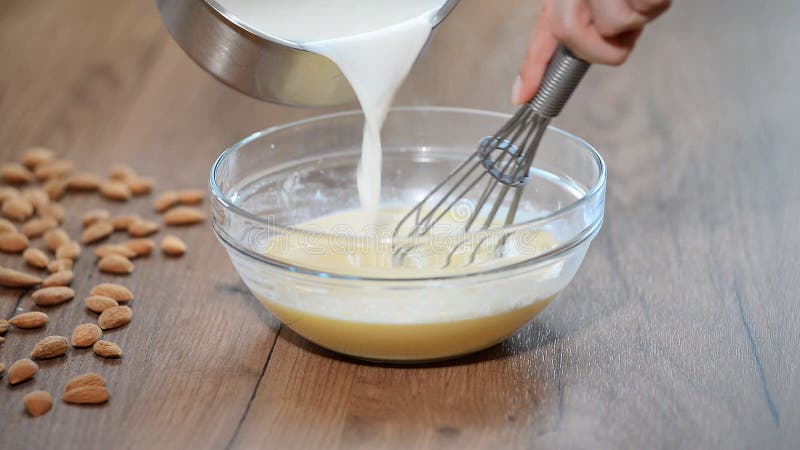 Een vrouw in de keuken om de vla te koken Melk het gieten in kom