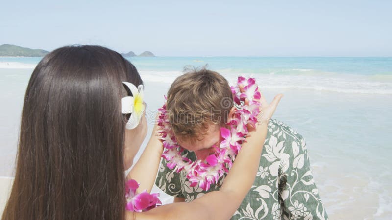 Een vrouw die garland rond de mannetjesnek aan het strand zet