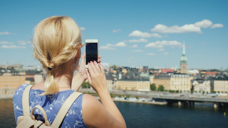 Een vrouw fotografeert een mooi beeld van de stad stockholm in zweden achteraanzicht. toerisme in scandinavië