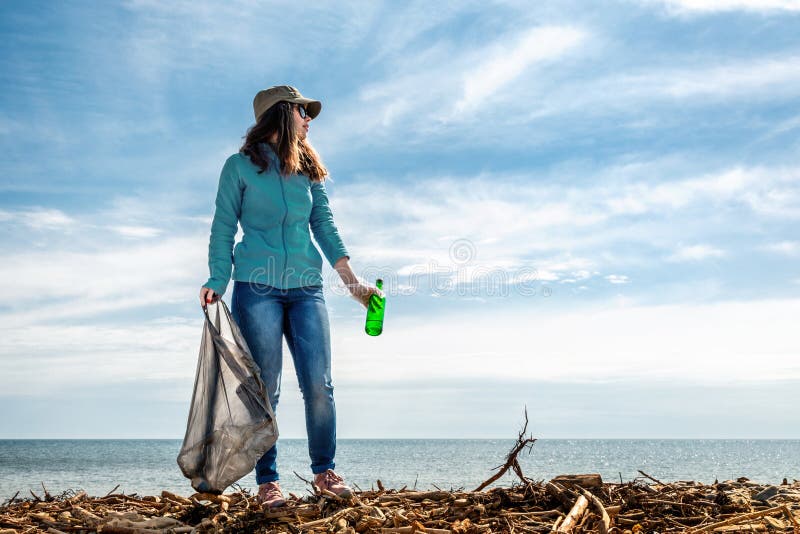Een vrouw op de vooravond van de Dag van de vakantieaarde verleent vrijwilligershulp in het schoonmaken van het kustgebied van pu stock foto's Een vrouw op de vooravond van de Dag van de vakantieaarde verleent vrijwilligershulp in het schoonmaken van het kustgebied van pu stock foto's