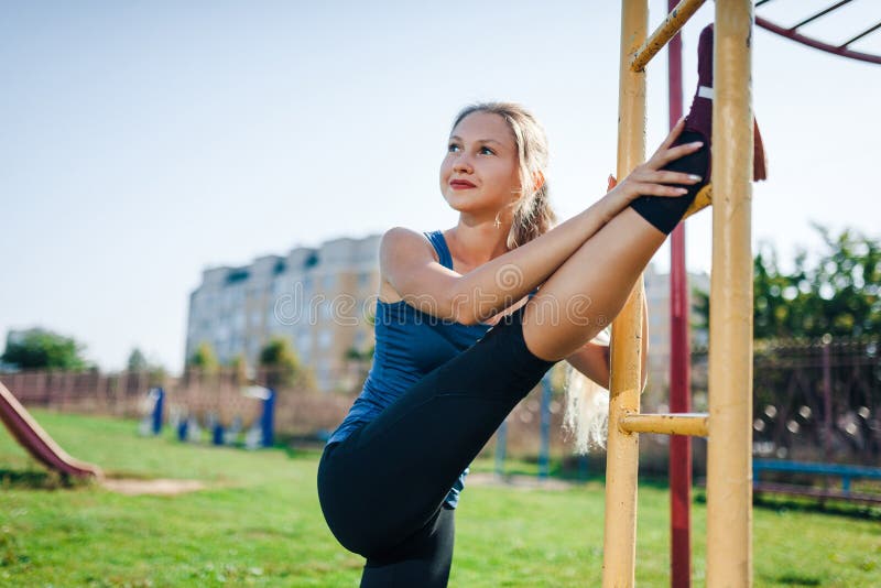 Een vrouw in sportkleding die opwarmingsoefeningen doen Stad in zonnige avond De geschikte geschiktheidsvrouw die het uitrekken d stock foto Een vrouw in sportkleding die opwarmingsoefeningen doen Stad in zonnige avond De geschikte geschiktheidsvrouw die het uitrekken d stock foto
