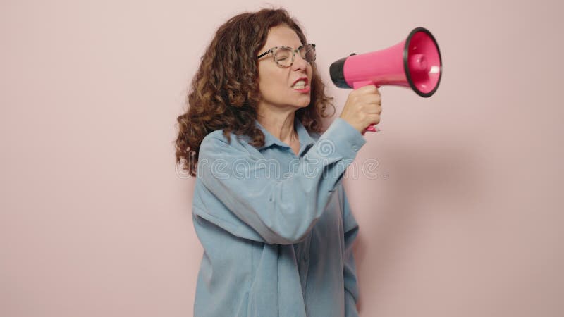 Een vrouw uit de middelbare leeftijd die boos is en megafoon gebruikt op roze achtergrond