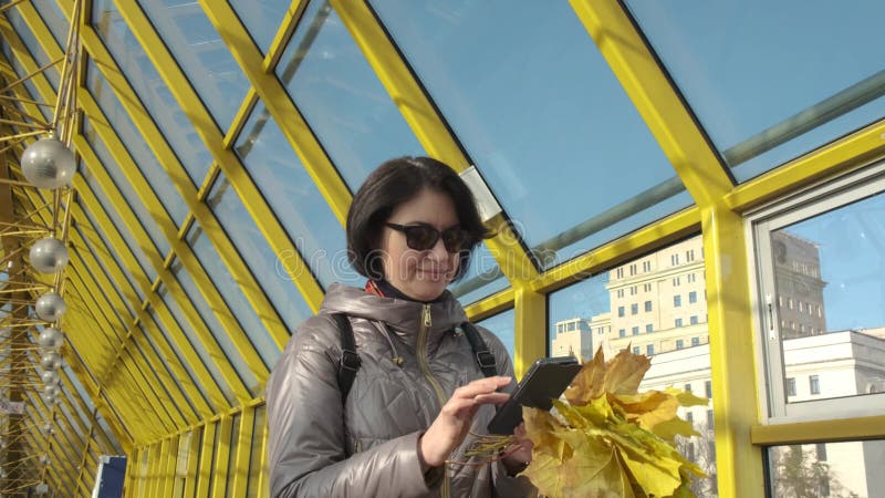 Een vrouw van middelbare leeftijd brunette caucasian met kort haar met een boeket van gele bladeren langs de voetbrug