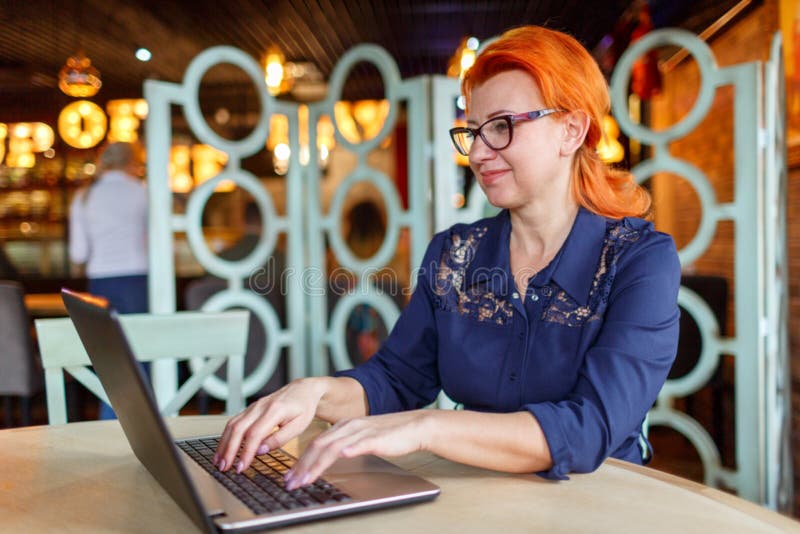 Een vrouw werkt achter laptop bij een lijst in een koffie Zachte nadruk stock afbeelding Een vrouw werkt achter laptop bij een lijst in een koffie Zachte nadruk stock afbeelding