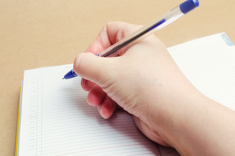 Een vrouwelijke hand schrijft in een notitieboekje en maakt nota's, plannen voor de dag, het winkelen lijst, close-up, maakt de z stock fotografie Een vrouwelijke hand schrijft in een notitieboekje en maakt nota's, plannen voor de dag, het winkelen lijst, close-up, maakt de z stock fotografie
