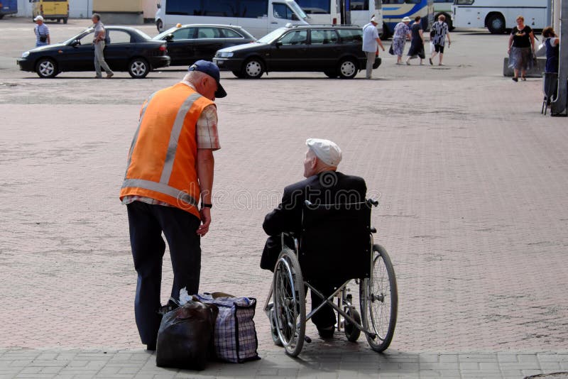 Chernihiv, Ukraine, June 7, 2019. A train station employee communicates with an elderly man in a wheelchair. Assistance to passengers with disabilities. Chernihiv, Ukraine, June 7, 2019. A train station employee communicates with an elderly man in a wheelchair. Assistance to passengers with disabilities