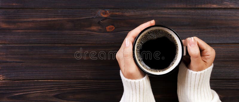 Eenzame vrouw het drinken koffie in de ochtend, hoogste mening van vrouwelijke handen die kop van hete drank op houten bureau hou royalty-vrije stock afbeelding Eenzame vrouw het drinken koffie in de ochtend, hoogste mening van vrouwelijke handen die kop van hete drank op houten bureau hou royalty-vrije stock afbeelding