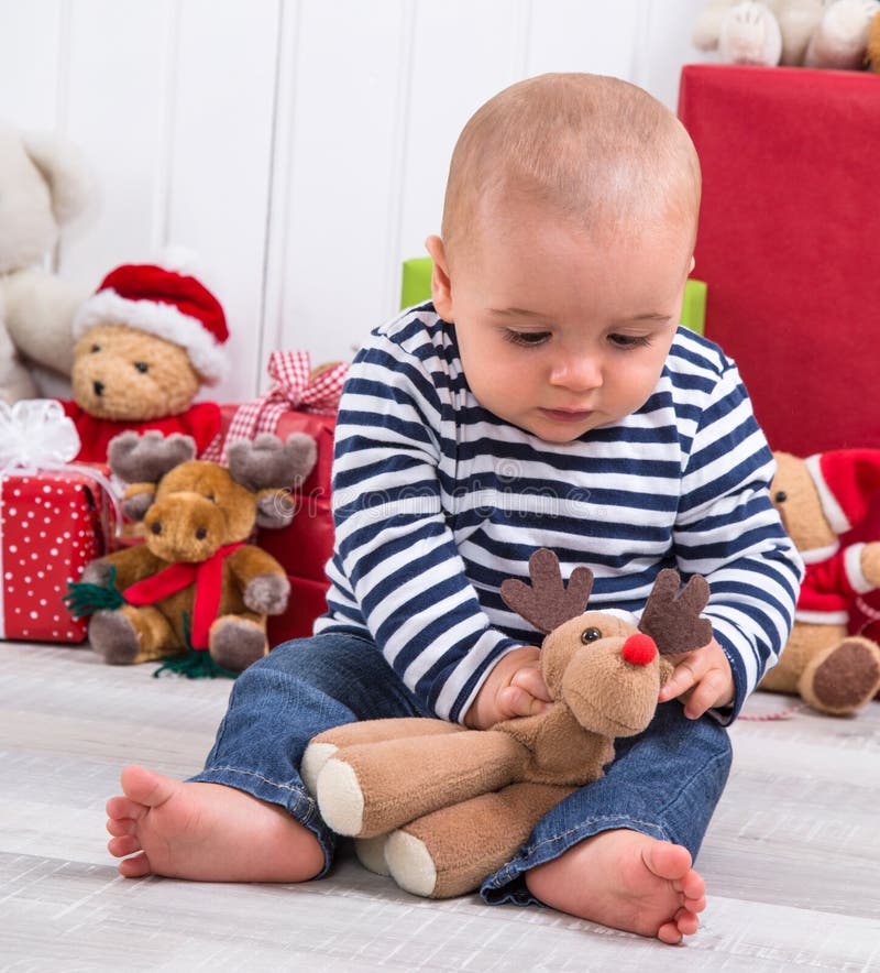 Eerste Kerstmis: baby die een heden opvouwen die - met a spelen plus royalty-vrije stock afbeelding Eerste Kerstmis: baby die een heden opvouwen die - met a spelen plus royalty-vrije stock afbeelding