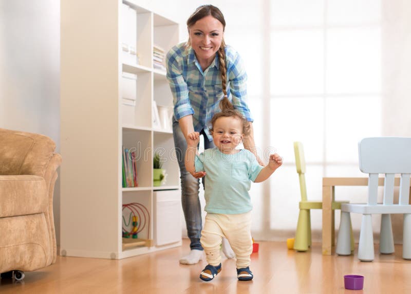 Eerste stappen van de jongen van de babypeuter het leren om in witte zonnige woonkamer te lopen Schoeisel voor kind royalty-vrije stock afbeeldingen Eerste stappen van de jongen van de babypeuter het leren om in witte zonnige woonkamer te lopen Schoeisel voor kind royalty-vrije stock afbeeldingen