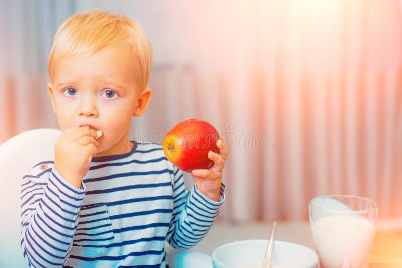 Eet gezond Peuter die snack hebben thuis Het kind eet havermoutpap Blauwe ogen van de jong geitje zitten de leuke jongen bij lijs stock afbeeldingen Eet gezond Peuter die snack hebben thuis Het kind eet havermoutpap Blauwe ogen van de jong geitje zitten de leuke jongen bij lijs stock afbeeldingen