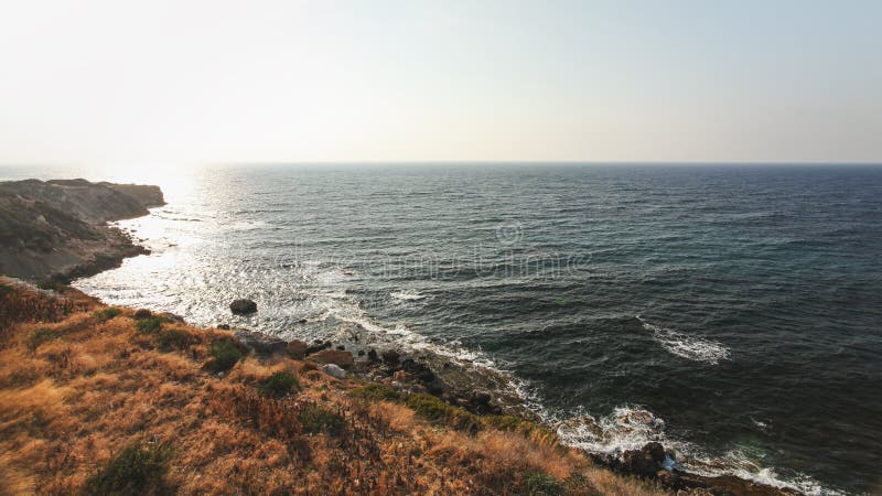 Eftermiddagsolen skiner på grov kust med steniga klippor och det djupa havet i den Karpass regionen av nordliga Cypern royaltyfri foto Eftermiddagsolen skiner på grov kust med steniga klippor och det djupa havet i den Karpass regionen av nordliga Cypern royaltyfri foto