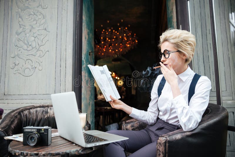 Eftertänksam kvinna som använder bärbara datorn och den läs- tidskriften i kafé royaltyfria bilder Eftertänksam kvinna som använder bärbara datorn och den läs- tidskriften i kafé royaltyfria bilder