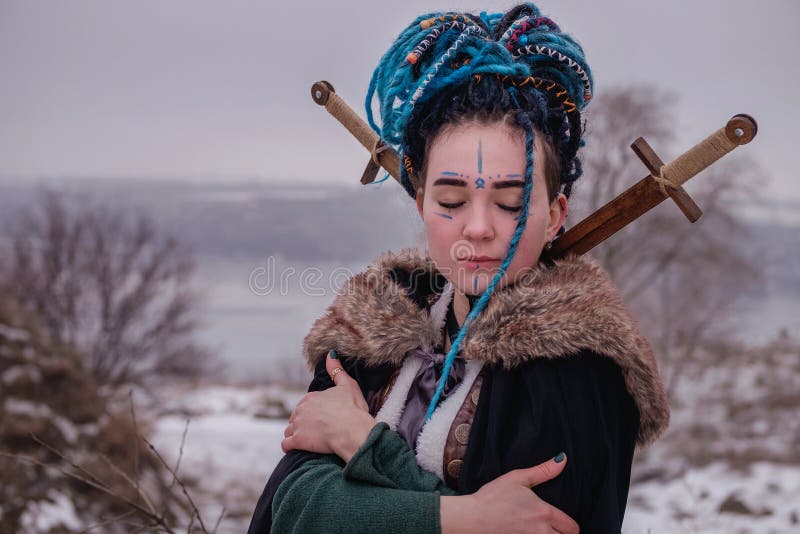 Eftertänksam vikingkvinna med ett svärd i ett svart långt ansvar med päls stående av en drömlik flicka med stängda ögon Kvinnlig royaltyfria bilder Eftertänksam vikingkvinna med ett svärd i ett svart långt ansvar med päls stående av en drömlik flicka med stängda ögon Kvinnlig royaltyfria bilder