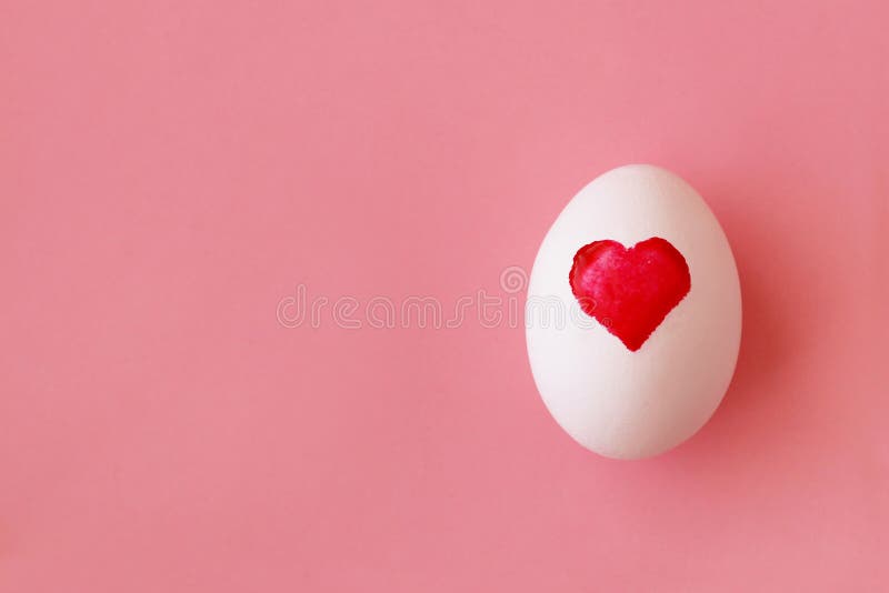 Egg with painted watercolor heart for Easter on the pink background