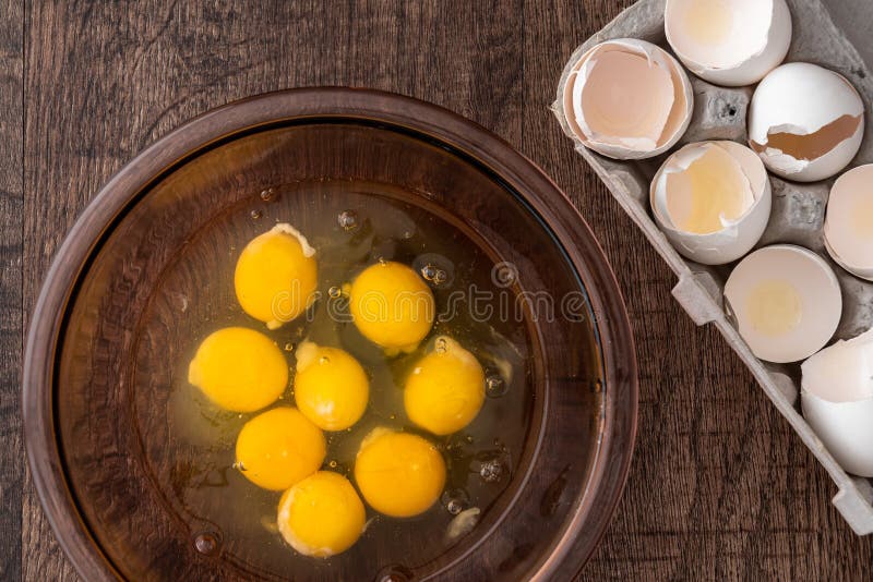 Egg Shells in Cardboard Egg Carton, Raw Eggs in Glass Bowl, on a Wood