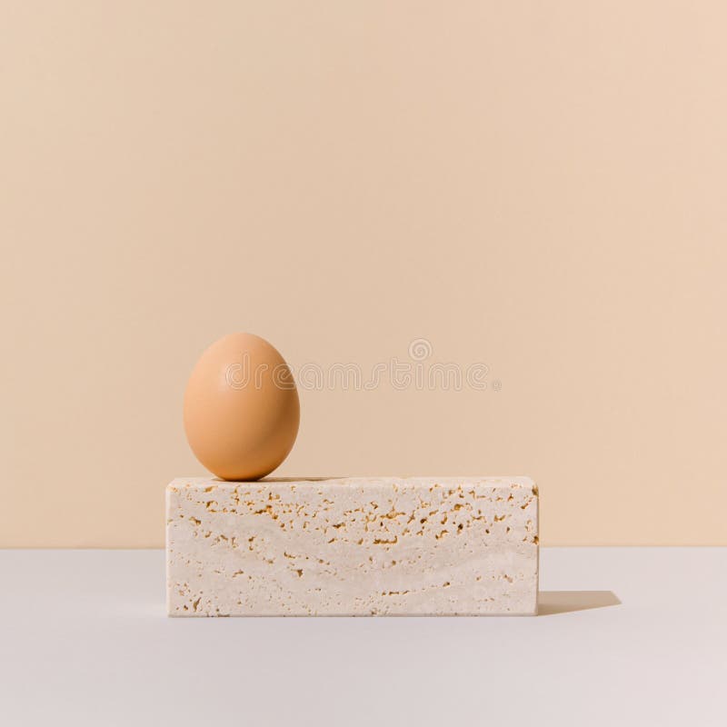 Egg on top of travertine marble block on a beige and gray background. 2021 Easter unique still life concept. stock image
