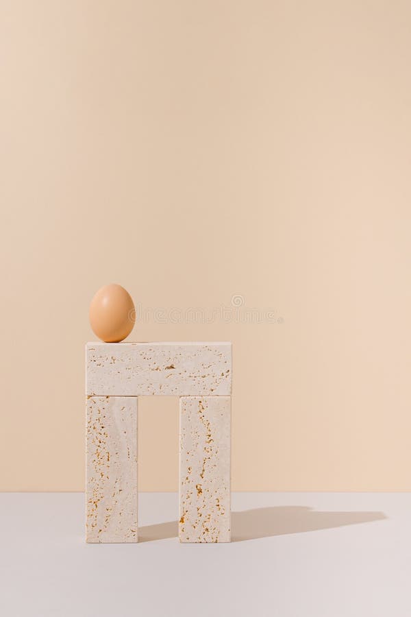 Egg on top of travertine marble blocks structure on a beige and gray background. 2021 Easter unique still life concept. stock photos