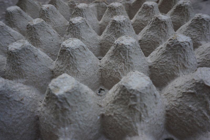 Cardboard egg trays with rows of conical shapes designed to securely hold eggs. The material is a textured, recycled paper pulp, typically gray in color. These trays are commonly used for packaging and transporting eggs, providing cushioning and protection against breakage. Their design ensures efficient stacking and space-saving storage. Cardboard color shapes stock images, royalty-free photos and pictures