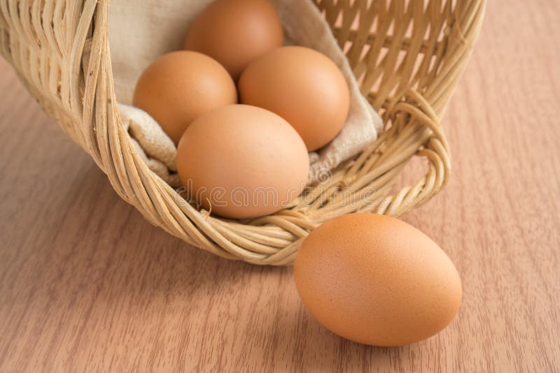 An egg on wooden table and eggs in wicker basket