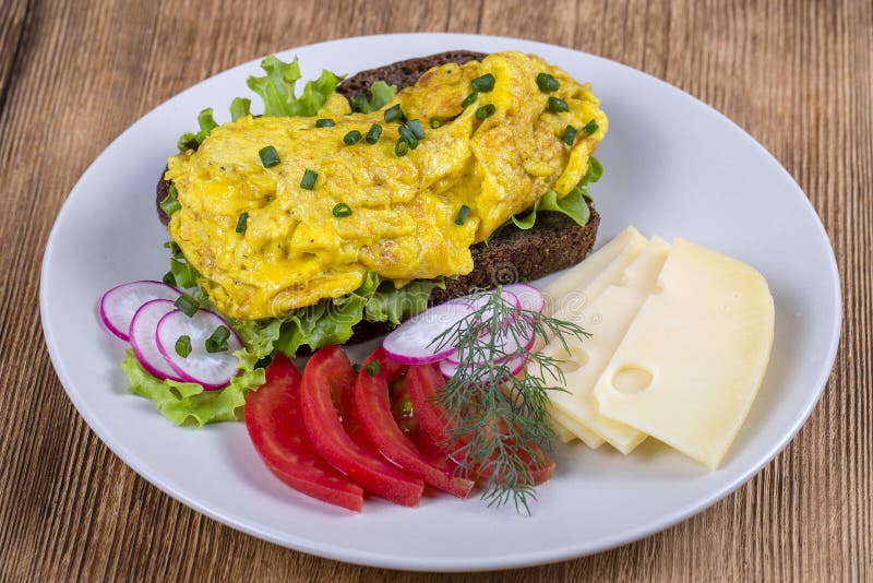 Egg омлет на части черного хлеба с красными томатами, сыром и редиской на деревянном столе, концом вверх стоковая фотография Egg омлет на части черного хлеба с красными томатами, сыром и редиской на деревянном столе, концом вверх стоковая фотография