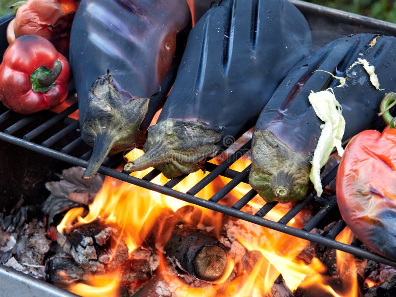 Roasting Eggplants and Red Peppers on a Grill Over an Open Fire Stock