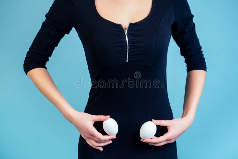 Eggs in the hands of a sexy girl in a black dress. The concept of ovaries, months and pms