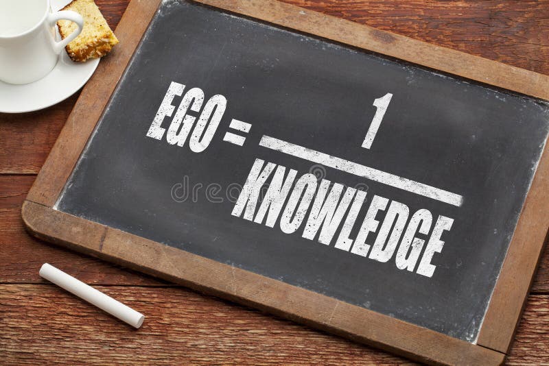 Ego and knowledge concept (illustration of Albert Einstein words) on a vintage slate blackboard with a chalk and cup of coffee