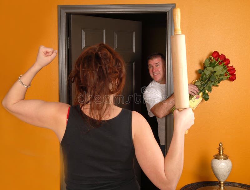 Husband coming home late to an angry wife who is holding a rolling pin. Husband coming home late to an angry wife who is holding a rolling pin