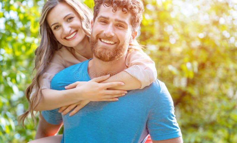 Ehemann tr? gt seine Frau auf seiner R? ckseite, die ein zuverl? ssiger Partner ist lizenzfreie stockfotos