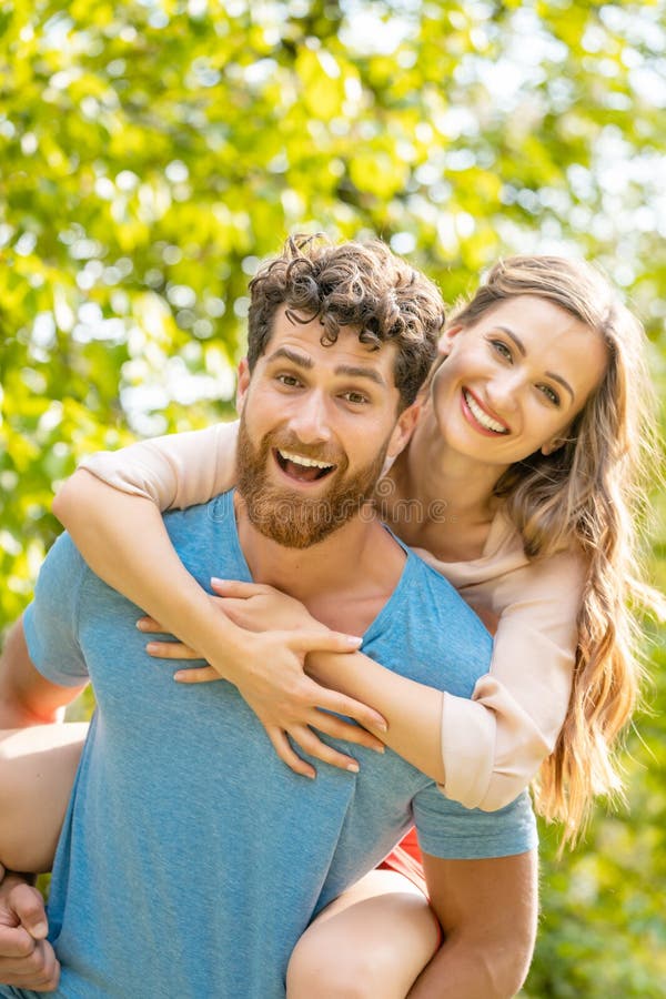 Ehemann tr? gt seine Frau auf seiner R? ckseite, die ein zuverl? ssiger Partner ist lizenzfreies stockfoto