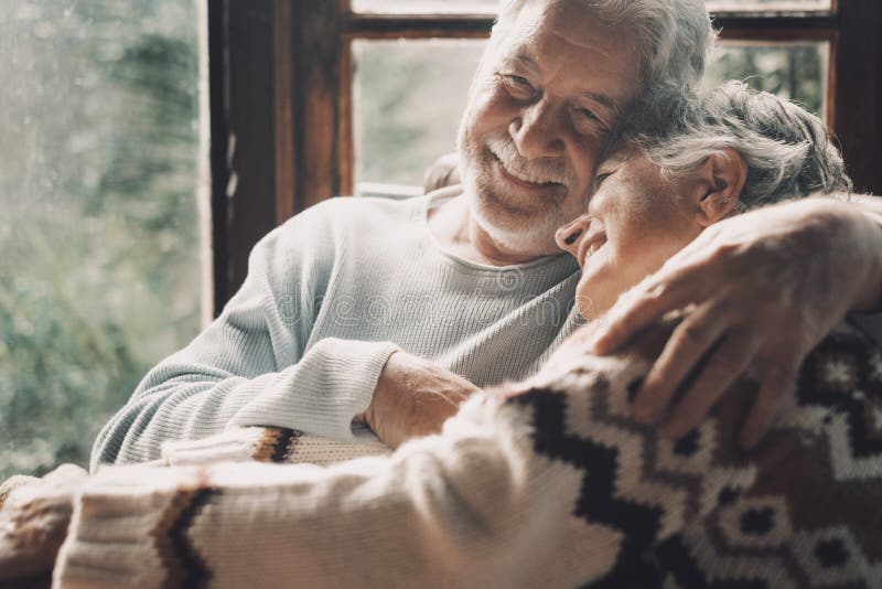 Ehepaar in Liebe und Umarmung mit Romantik zusammen zu Hause mit Blick von außen in Windows-Hintergrund glücklich reifen lizenzfreie stockbilder