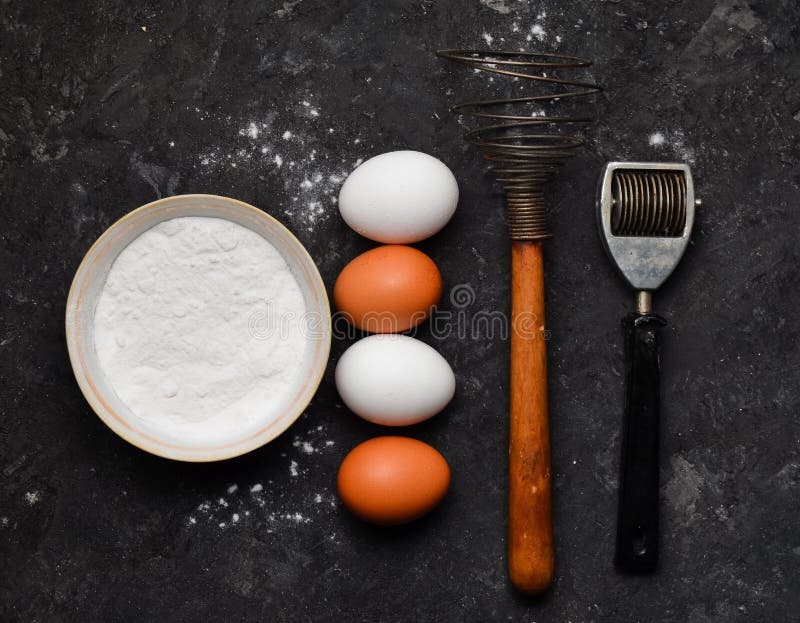 Eieren, bloem, keukengereedschap op een zwarte concrete lijst Ingrediënten voor deegwaren Het het koken procédé Hulpmiddelen om T royalty-vrije stock fotografie Eieren, bloem, keukengereedschap op een zwarte concrete lijst Ingrediënten voor deegwaren Het het koken procédé Hulpmiddelen om T royalty-vrije stock fotografie