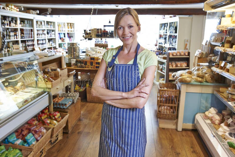 Eigenaar die van Delicatessen zich in Winkel bevinden stock fotografie Eigenaar die van Delicatessen zich in Winkel bevinden stock fotografie