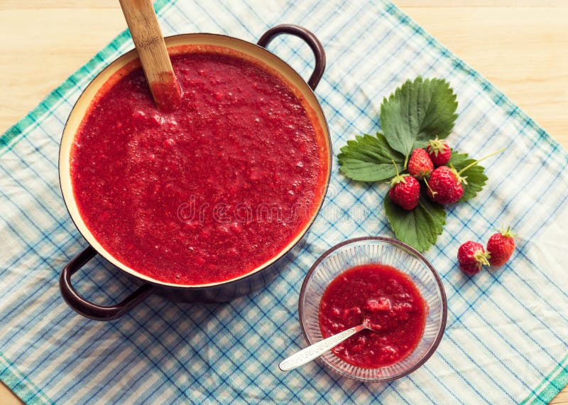 Eigengemaakte aardbeijam die (marmelade) koken Grote pot met hete jam en verse aardbeien royalty-vrije stock afbeelding Eigengemaakte aardbeijam die (marmelade) koken Grote pot met hete jam en verse aardbeien royalty-vrije stock afbeelding