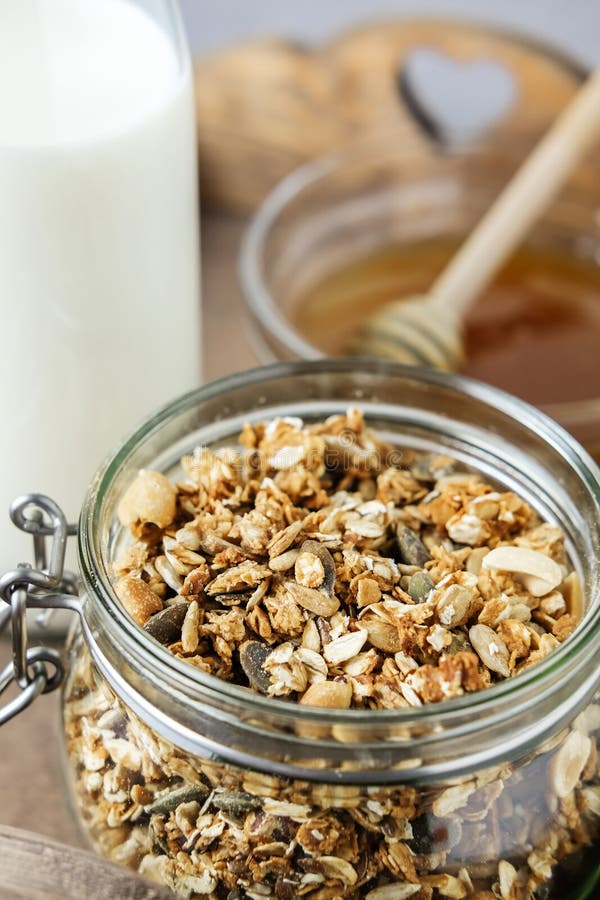 Eigengemaakte granola in een glaskruik op een houten dienblad en een fles melk en honing Nuttig ontbijt royalty-vrije stock fotografie Eigengemaakte granola in een glaskruik op een houten dienblad en een fles melk en honing Nuttig ontbijt royalty-vrije stock fotografie