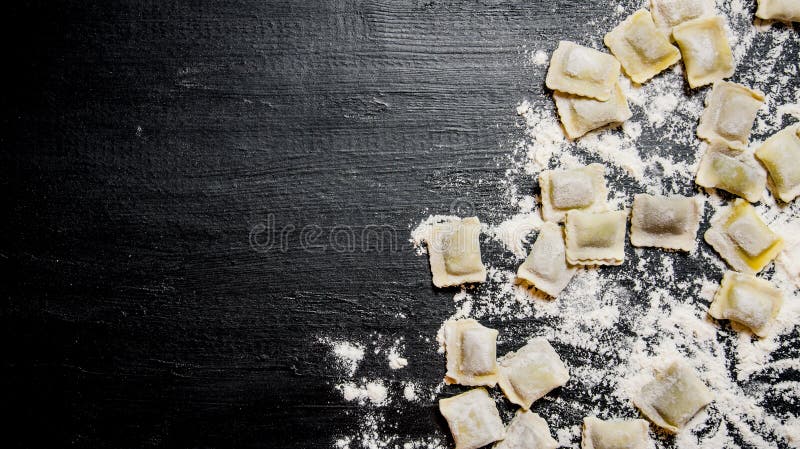 Homemade ravioli with flour. On the black table with flour. Free space for text . Top view. Homemade ravioli with flour. On the black table with flour. Free space for text . Top view