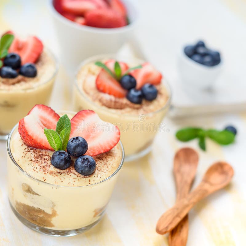 eigengemaakte, uitstekende die desserttiramisu in glazen met aardbei, bosbes, munt op witte houten lijst, hoogste mening worden v stock afbeeldingen eigengemaakte, uitstekende die desserttiramisu in glazen met aardbei, bosbes, munt op witte houten lijst, hoogste mening worden v stock afbeeldingen