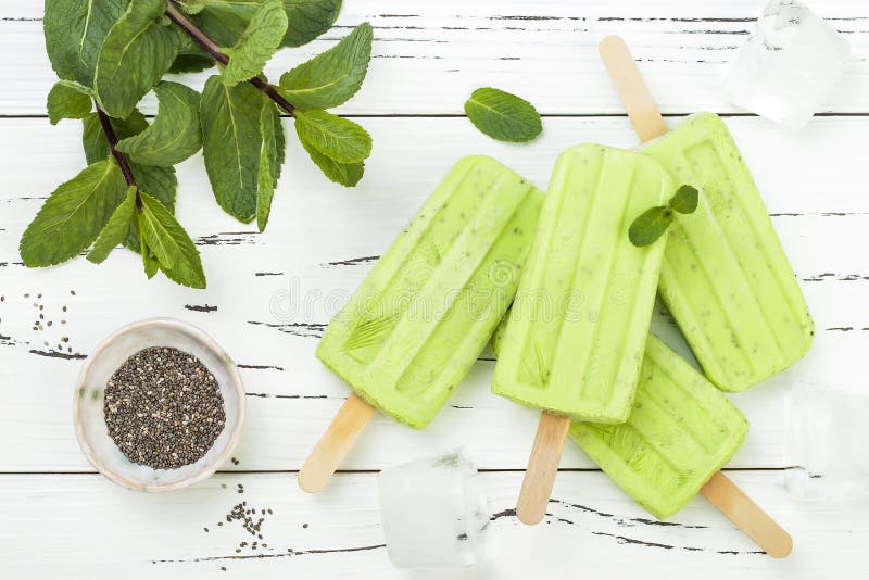 Eigengemaakte van de matchamunt van de veganist groene thee de kokosmelkijslollys met chiazaden op rustieke witte houten achtergr stock foto's Eigengemaakte van de matchamunt van de veganist groene thee de kokosmelkijslollys met chiazaden op rustieke witte houten achtergr stock foto's