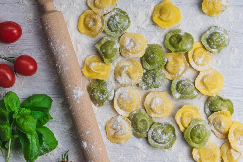 Homemade fresh Italian ravioli pasta on white wood table with flour, basil, tomatoes,background, top view. Homemade fresh Italian ravioli pasta on white wood table with flour, basil, tomatoes,background, top view