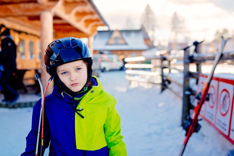 Eight years old boy in helmet on ski slope.