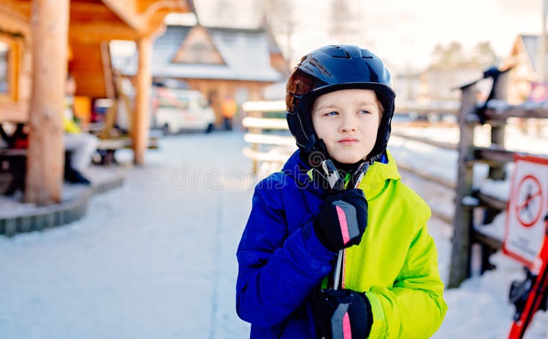 Eight years old boy in helmet on ski slope.