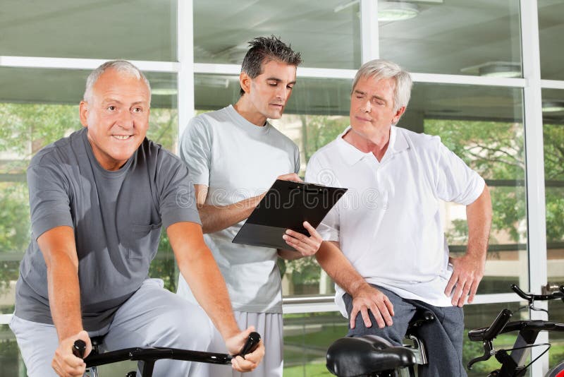 Fitness trainer with clipboard coaching happy senior people in gym. Fitness trainer with clipboard coaching happy senior people in gym