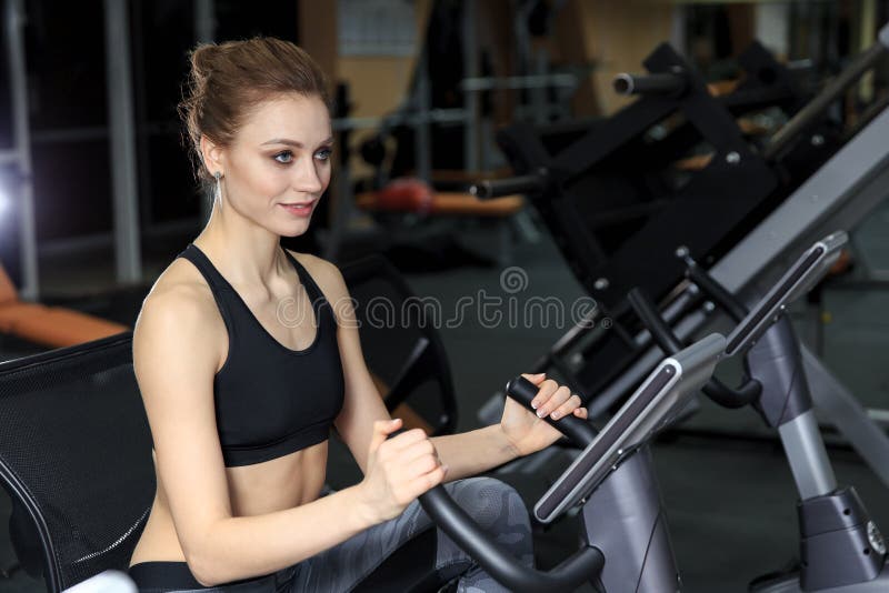 Eignungs-Mädchen, das auf Fahrrad in einer modernen Eignungs-Mitte trainiert lizenzfreies stockbild Eignungs-Mädchen, das auf Fahrrad in einer modernen Eignungs-Mitte trainiert lizenzfreies stockbild