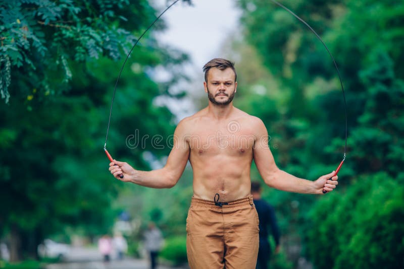Eignungs-, Sport-, Trainings- und Lebensstilkonzept - bloß-chested Springen des gesunden Athleten mit dem Springseil im Freien stockbild Eignungs-, Sport-, Trainings- und Lebensstilkonzept - bloß-chested Springen des gesunden Athleten mit dem Springseil im Freien stockbild