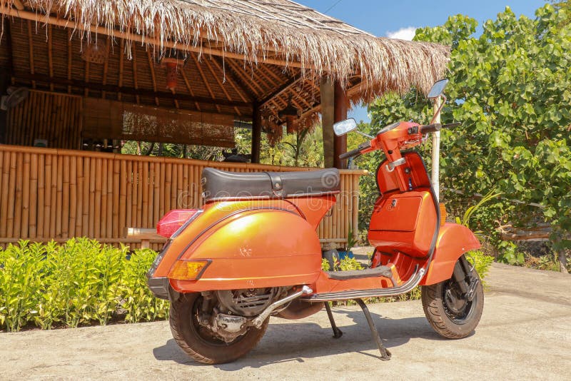 Ein alter italienischer Roller geparkt vor einem Bambusgebäude Orange klassischer Trübsal geblasener Vespa aus Italien Hintergrun stockfoto Ein alter italienischer Roller geparkt vor einem Bambusgebäude Orange klassischer Trübsal geblasener Vespa aus Italien Hintergrun stockfoto