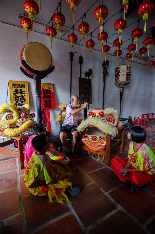Ein alter Mann den chinesischen Löwetanzkopf mit Pinsel reinigen. Georgetown-penangmalaysia am 8. Juli 2016 : ein alter Mann, den chinesischen Löwetanzkopf mit Pinsel mit Jugendlichen zu reinigen sitzen am Boden.