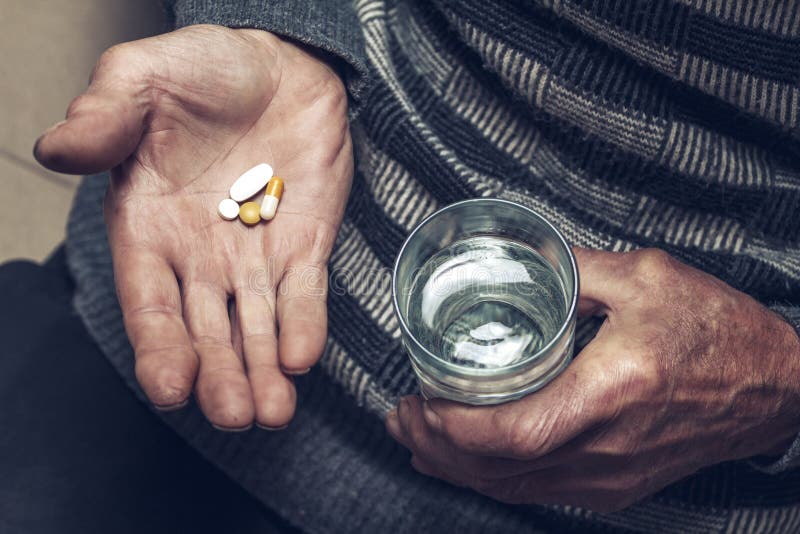 Ein alter Mann nimmt Tabletten mit einem Glas Wasser stockfotos