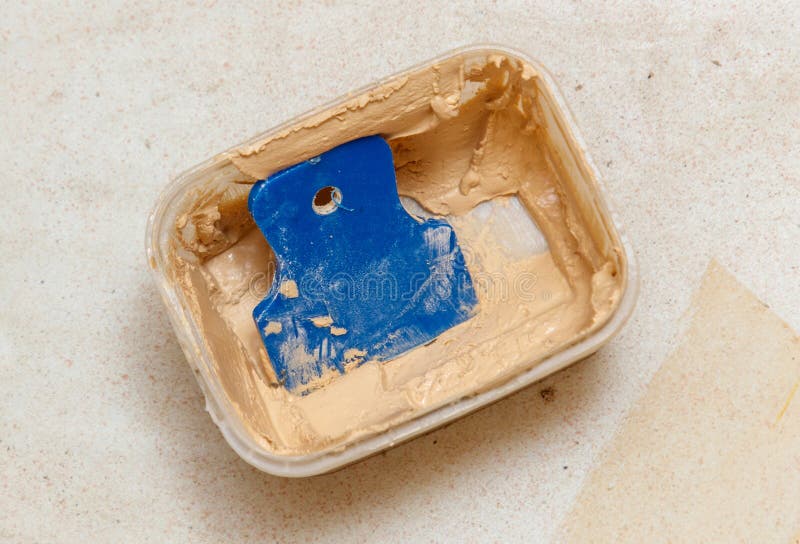 Ein blaues Spatel sitzt in einem Behälter mit brauner Farbe stockfotos