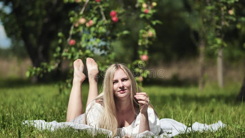 Ein blondes Mädchen liegt in einer Räumung in einem Apfelgarten.
